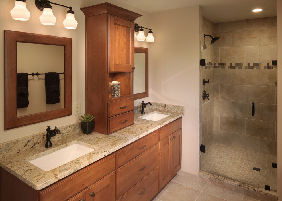 This is an example of a mid-sized traditional master bathroom in Denver with an undermount sink, flat-panel cabinets, medium wood cabinets, granite benchtops, an alcove shower, a two-piece toilet, beige tile, porcelain tile and porcelain floors.