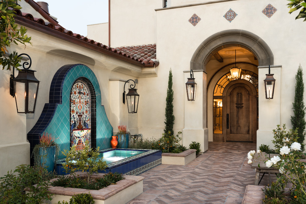 Mediterranean front door in Orange County with a single front door, a dark wood front door and white walls.