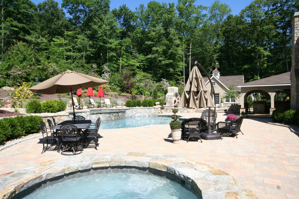 Design ideas for a transitional backyard custom-shaped natural pool in Bridgeport with a hot tub and natural stone pavers.