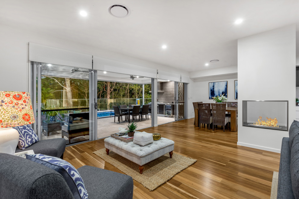 Design ideas for a mid-sized open concept living room in Brisbane with white walls, medium hardwood floors, a freestanding tv and brown floor.