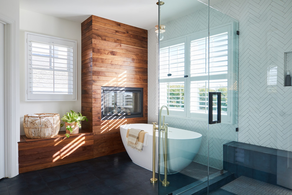 Design ideas for a beach style master bathroom in Los Angeles with a freestanding tub, white tile, white walls, black floor and a hinged shower door.