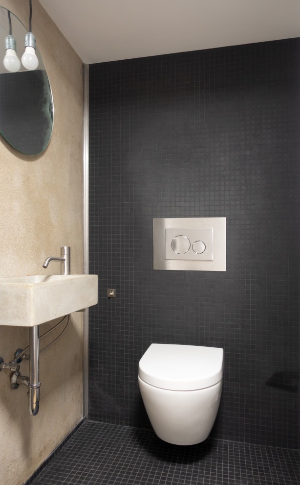 Свежая идея для дизайна: маленький туалет в современном стиле с инсталляцией, черной плиткой, плиткой мозаикой, бежевыми стенами, полом из мозаичной плитки, подвесной раковиной, столешницей из бетона, черным полом и серой столешницей для на участке и в саду - отличное фото интерьера