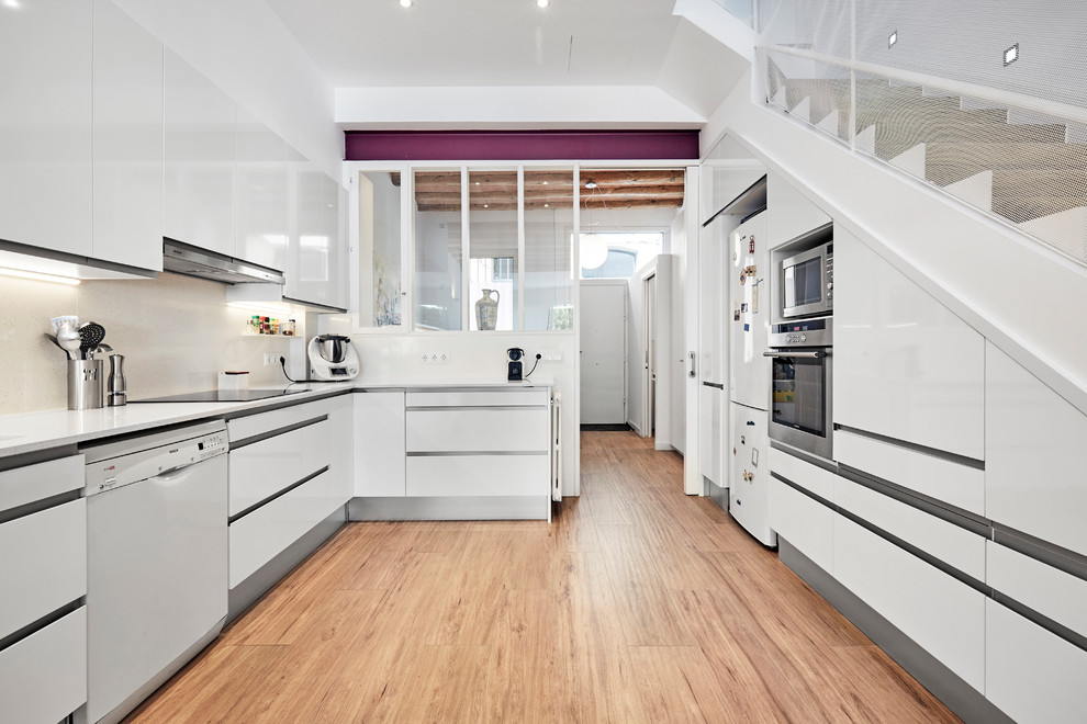 Design ideas for a contemporary u-shaped separate kitchen in Other with flat-panel cabinets, white cabinets, beige splashback, white appliances, medium hardwood floors, no island, beige floor and white benchtop.
