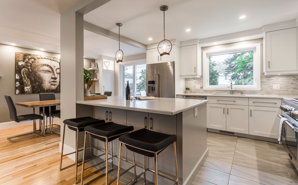 Mid-sized transitional l-shaped porcelain tile and gray floor eat-in kitchen photo with an undermount sink, flat-panel cabinets, gray cabinets, quartz countertops, multicolored backsplash, matchstick tile backsplash, stainless steel appliances and an island