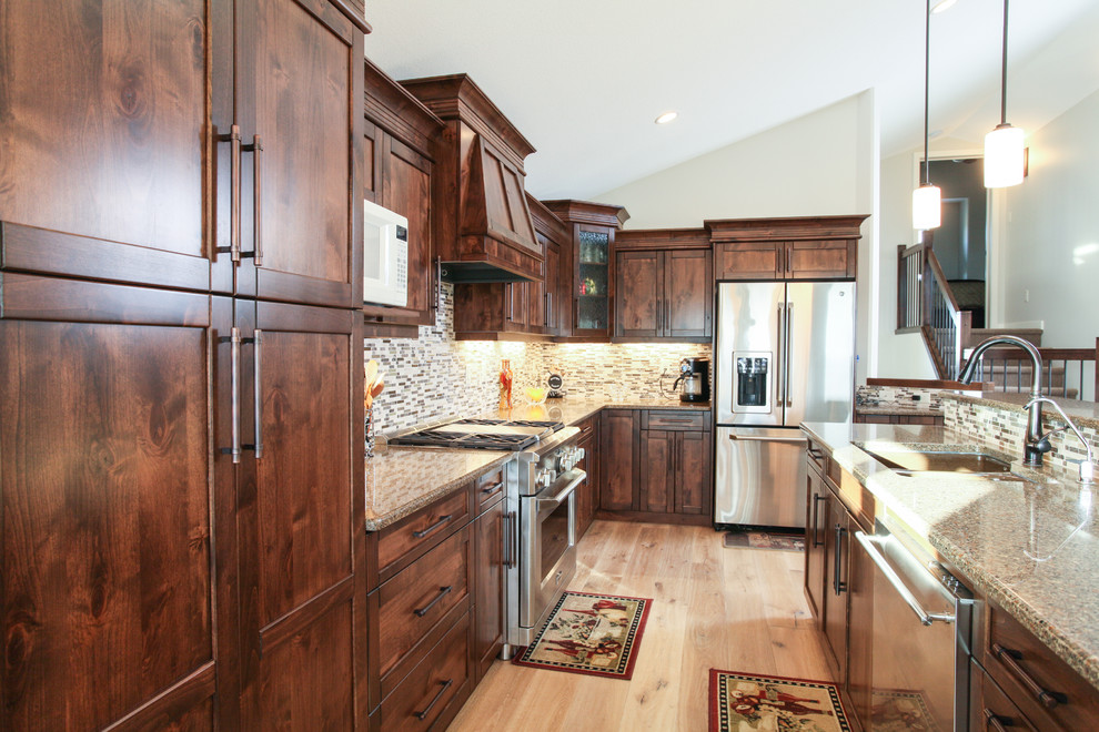 Inspiration for a transitional l-shaped light wood floor eat-in kitchen remodel in Calgary with an undermount sink, shaker cabinets, dark wood cabinets, quartz countertops, gray backsplash, matchstick tile backsplash, stainless steel appliances and an island