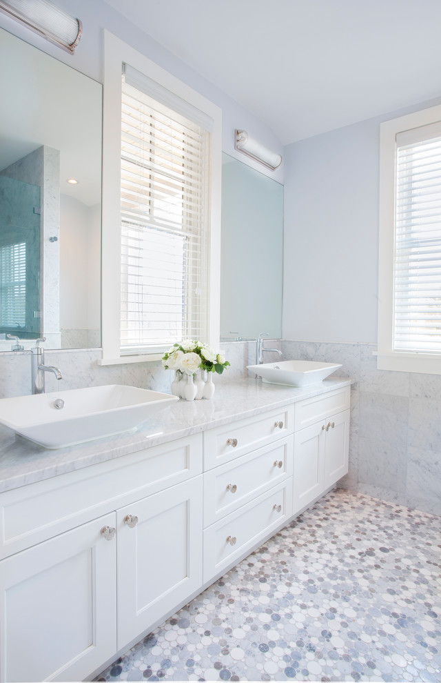 Photo of a beach style master bathroom in Boston with a vessel sink, recessed-panel cabinets, white cabinets, gray tile, stone tile and white walls.