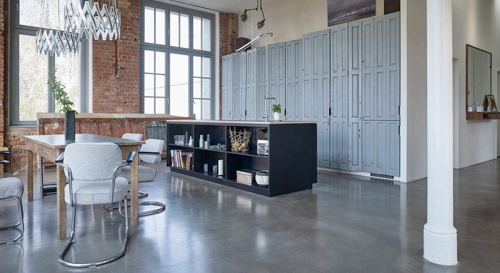 Photo of an expansive industrial single-wall eat-in kitchen in Leipzig with beaded inset cabinets, grey cabinets, concrete floors and with island.