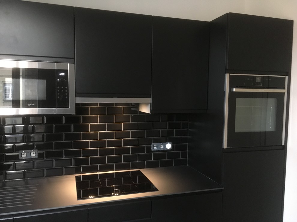 Small contemporary single-wall separate kitchen in Reims with a single-bowl sink, flat-panel cabinets, black cabinets, laminate benchtops, black splashback, subway tile splashback, stainless steel appliances, cement tiles and multi-coloured floor.