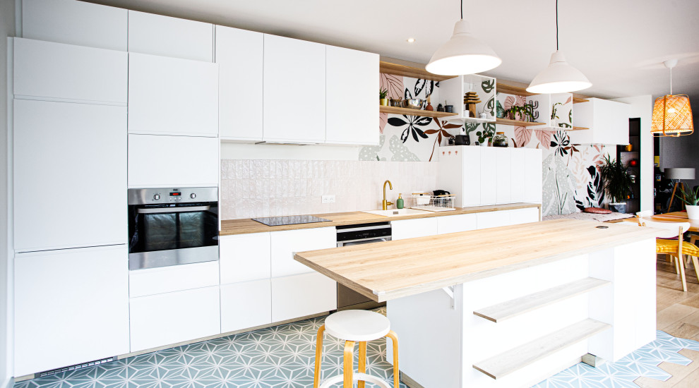 Expansive modern single-wall open plan kitchen in Paris with a single-bowl sink, white cabinets, wood benchtops, ceramic splashback, stainless steel appliances, with island and turquoise floor.