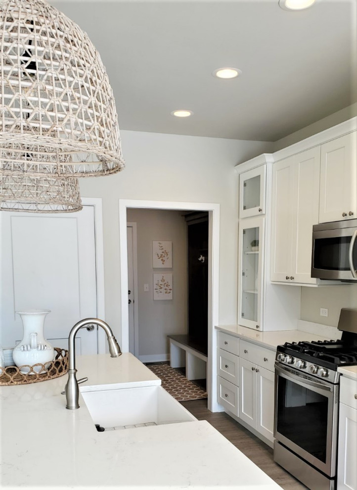 Eat-in kitchen - mid-sized transitional galley vinyl floor and brown floor eat-in kitchen idea in Chicago with a farmhouse sink, shaker cabinets, white cabinets, quartz countertops, stainless steel appliances, an island and white countertops