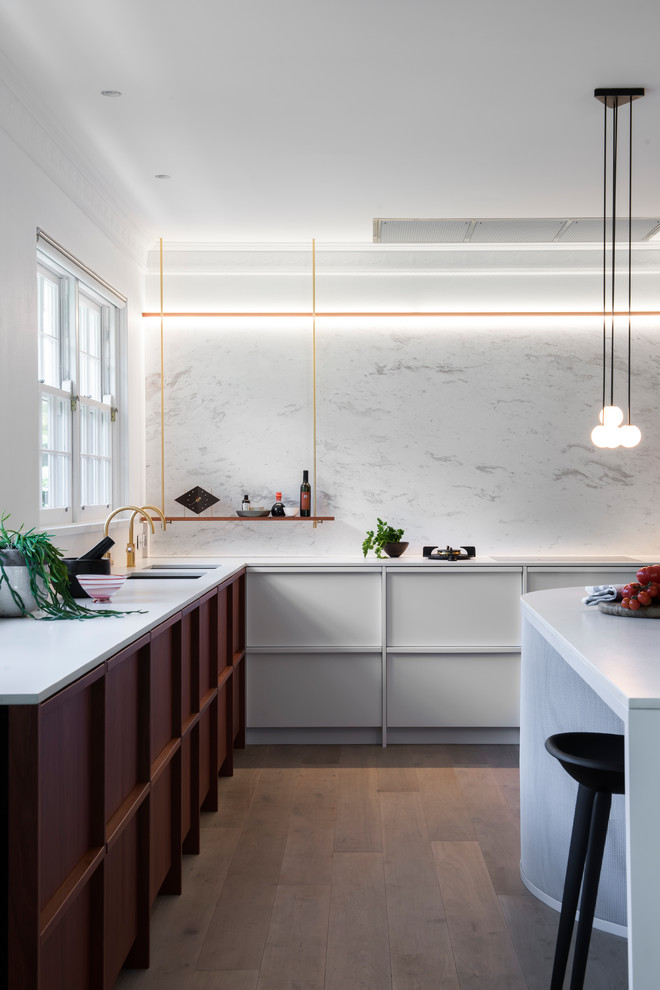 Design ideas for a large contemporary u-shaped open plan kitchen in Sydney with an undermount sink, raised-panel cabinets, white cabinets, quartz benchtops, white splashback, marble splashback, black appliances, light hardwood floors and with island.