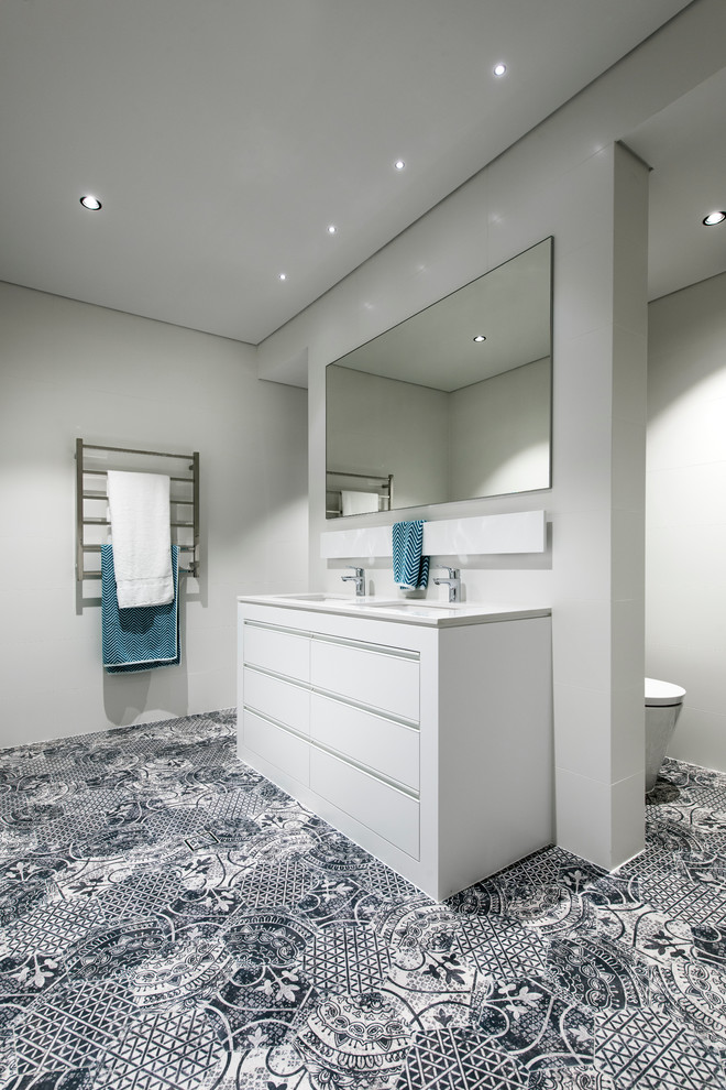 This is an example of a mid-sized mediterranean 3/4 bathroom in Perth with furniture-like cabinets, white cabinets, engineered quartz benchtops, multi-coloured tile and porcelain tile.