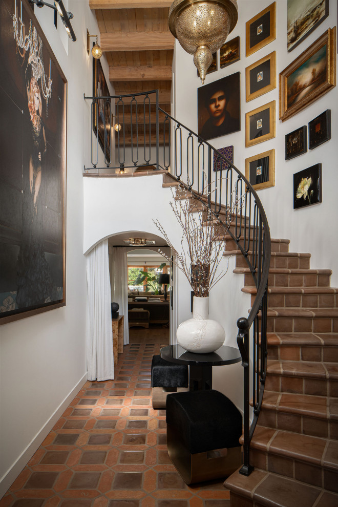 Стильный дизайн: изогнутая лестница в стиле фьюжн с ступенями из терракотовой плитки, подступенками из терракотовой плитки и металлическими перилами - последний тренд
