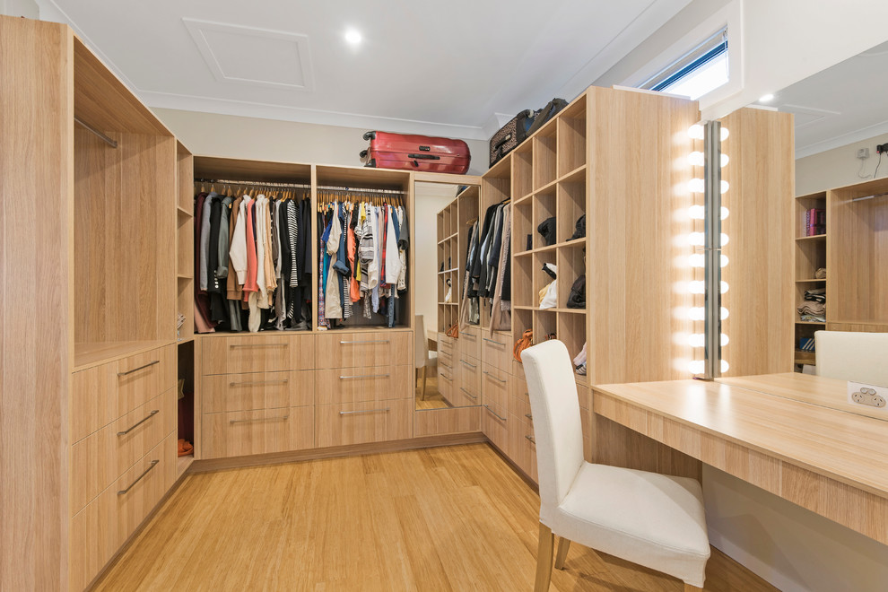 Mid-sized contemporary gender-neutral walk-in wardrobe in Brisbane with light wood cabinets, bamboo floors, flat-panel cabinets and beige floor.