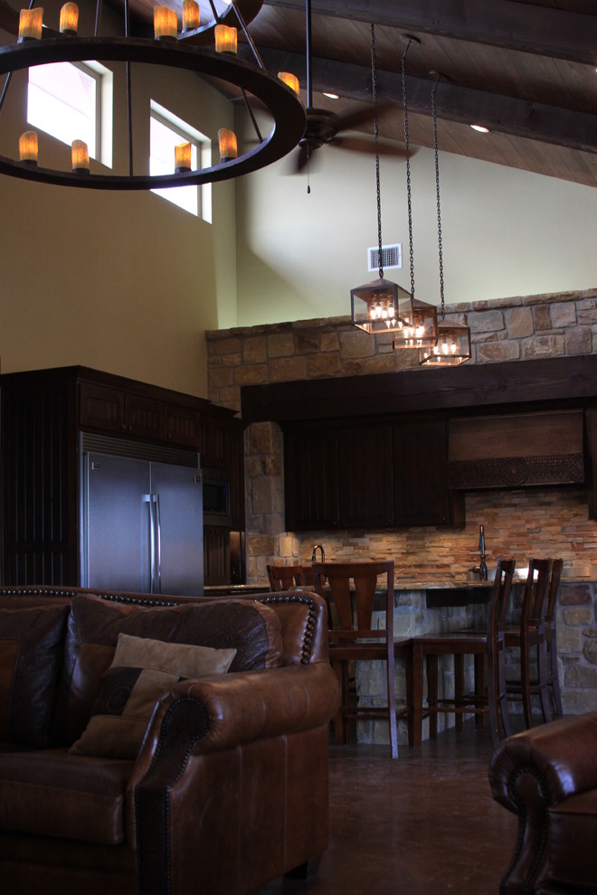 Mountain style galley concrete floor open concept kitchen photo in Austin with a farmhouse sink, beaded inset cabinets, dark wood cabinets, granite countertops, stainless steel appliances and a peninsula