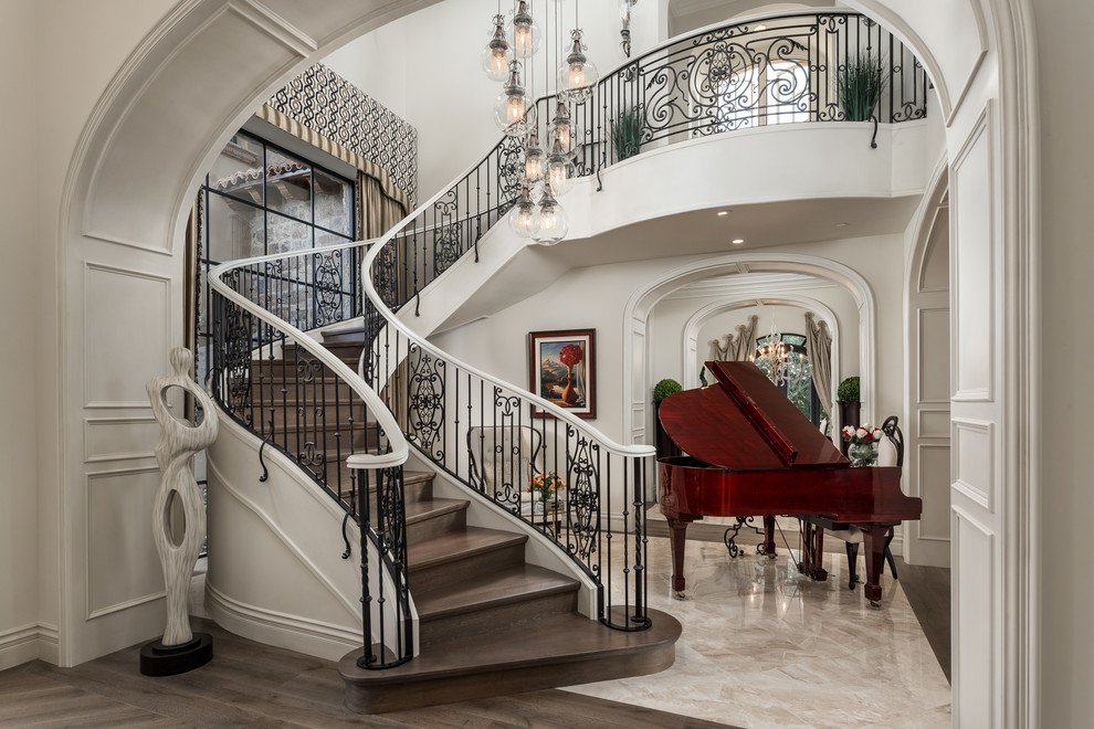 This is an example of an expansive traditional wood floating staircase in Phoenix with wood risers and metal railing.