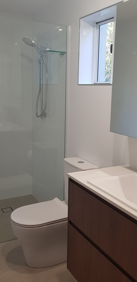 This is an example of a small modern bathroom in Brisbane with medium wood cabinets, an open shower, a one-piece toilet, white tile, porcelain tile, porcelain floors, a drop-in sink, engineered quartz benchtops, beige floor, an open shower and white benchtops.