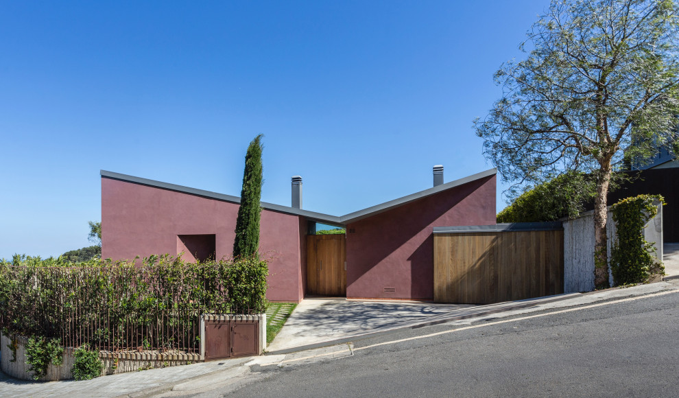 Contemporary purple house exterior in Barcelona with a butterfly roof and a grey roof.