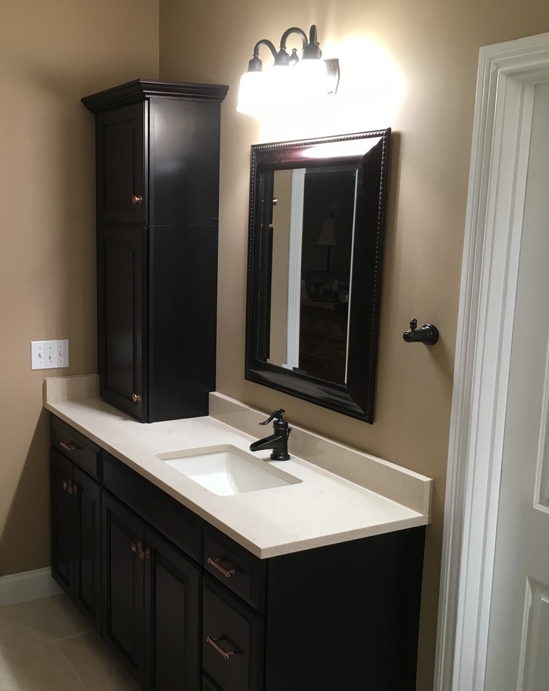 Design ideas for a traditional master bathroom in Cincinnati with raised-panel cabinets, dark wood cabinets, a drop-in tub, a corner shower, beige tile, porcelain tile, brown walls, travertine floors, an undermount sink and marble benchtops.
