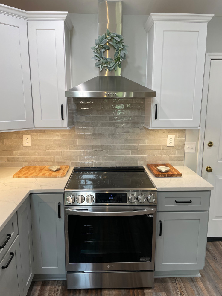 Example of a mid-sized transitional u-shaped vinyl floor and brown floor eat-in kitchen design with shaker cabinets, white cabinets, quartz countertops, gray backsplash, subway tile backsplash, stainless steel appliances, no island and white countertops