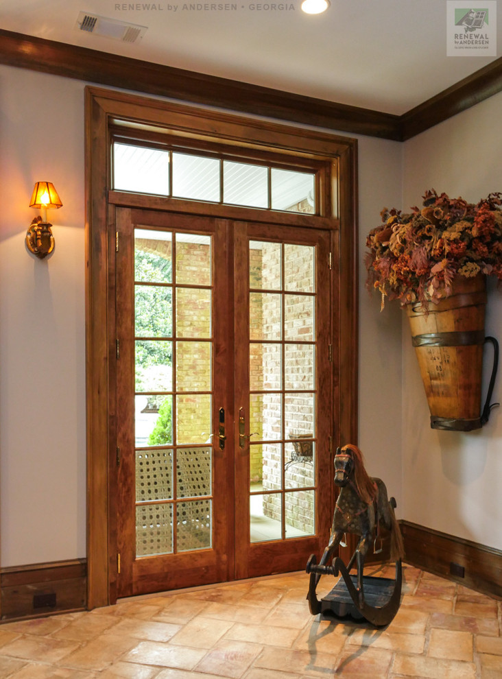 Modelo de entrada de tamaño medio con paredes beige, suelo de baldosas de cerámica, puerta de madera en tonos medios y suelo beige
