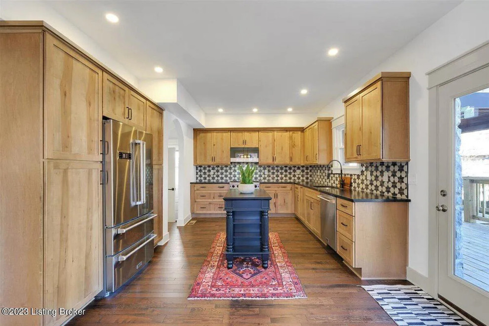 Example of a transitional medium tone wood floor kitchen design with an undermount sink, shaker cabinets, light wood cabinets and an island