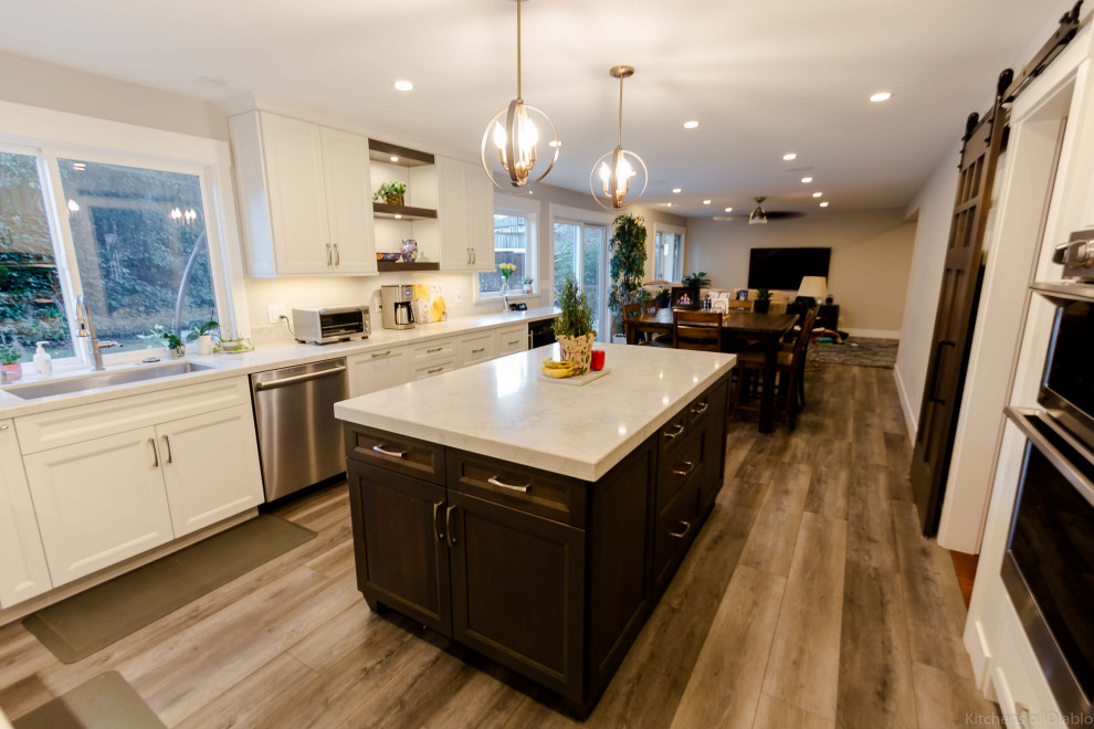 Inspiration for a large transitional u-shaped medium tone wood floor and gray floor open concept kitchen remodel in San Francisco with an undermount sink, recessed-panel cabinets, white cabinets, quartz countertops, white backsplash, marble backsplash, stainless steel appliances, an island and white countertops