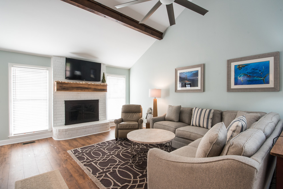 Mid-sized country open concept living room in Charleston with blue walls, medium hardwood floors, a standard fireplace, a brick fireplace surround and a wall-mounted tv.