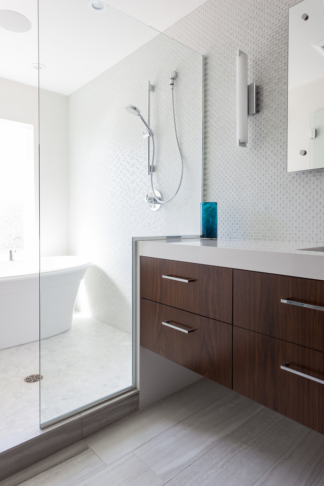 This is an example of a large modern master bathroom in Minneapolis with a trough sink, flat-panel cabinets, dark wood cabinets, engineered quartz benchtops, a freestanding tub, a double shower, a two-piece toilet, white tile, glass tile, grey walls and ceramic floors.