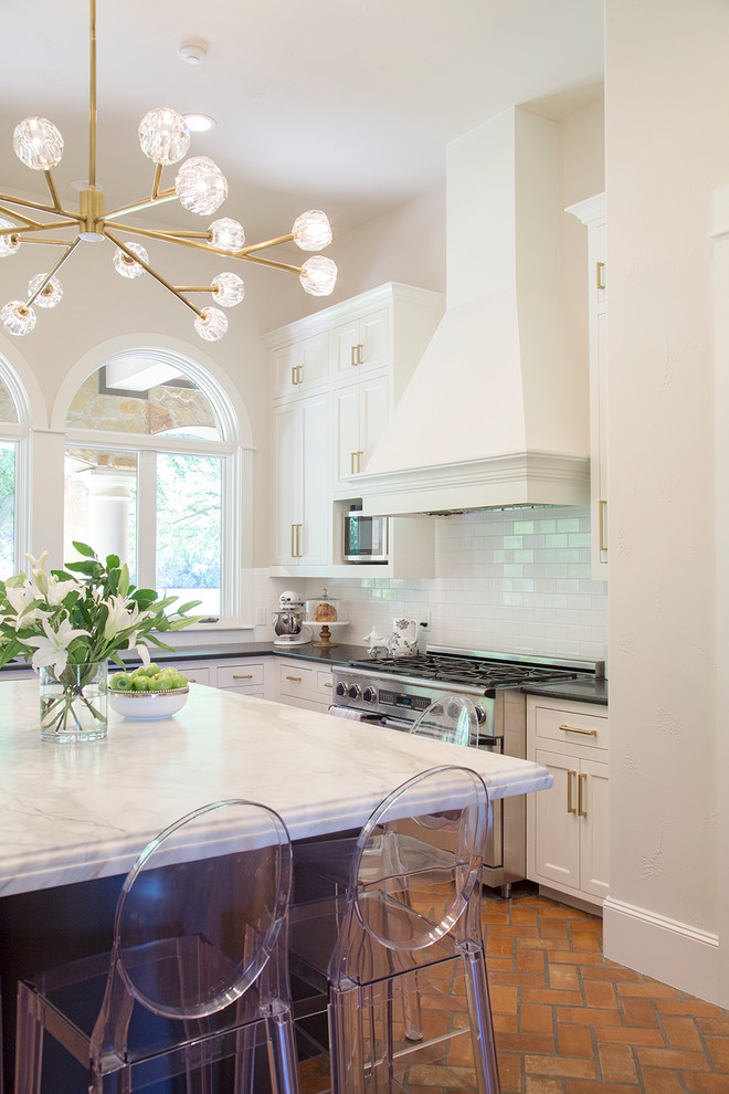 Kitchen - huge transitional u-shaped brick floor kitchen idea in Austin with white cabinets, marble countertops, white backsplash, subway tile backsplash, stainless steel appliances and an island