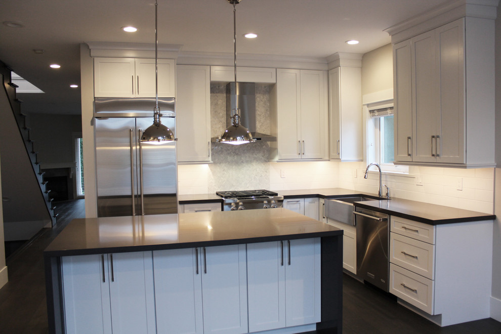 Inspiration for a large traditional l-shaped open plan kitchen in Vancouver with an undermount sink, shaker cabinets, white cabinets, quartz benchtops, white splashback, ceramic splashback, stainless steel appliances, dark hardwood floors and with island.