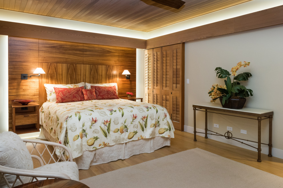 Inspiration for a tropical bedroom in Hawaii with beige walls, medium hardwood floors and brown floor.