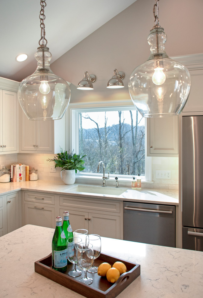 Inspiration for a transitional vaulted ceiling eat-in kitchen remodel with an undermount sink, shaker cabinets, white cabinets, quartz countertops, white backsplash, ceramic backsplash, stainless steel appliances, an island and white countertops