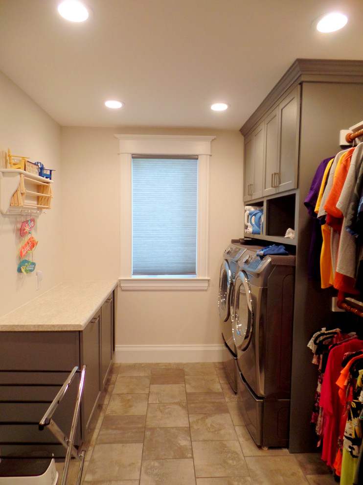 Photo of a mid-sized transitional galley laundry room in Cedar Rapids with flat-panel cabinets, grey cabinets, laminate benchtops, porcelain floors, a side-by-side washer and dryer and beige walls.