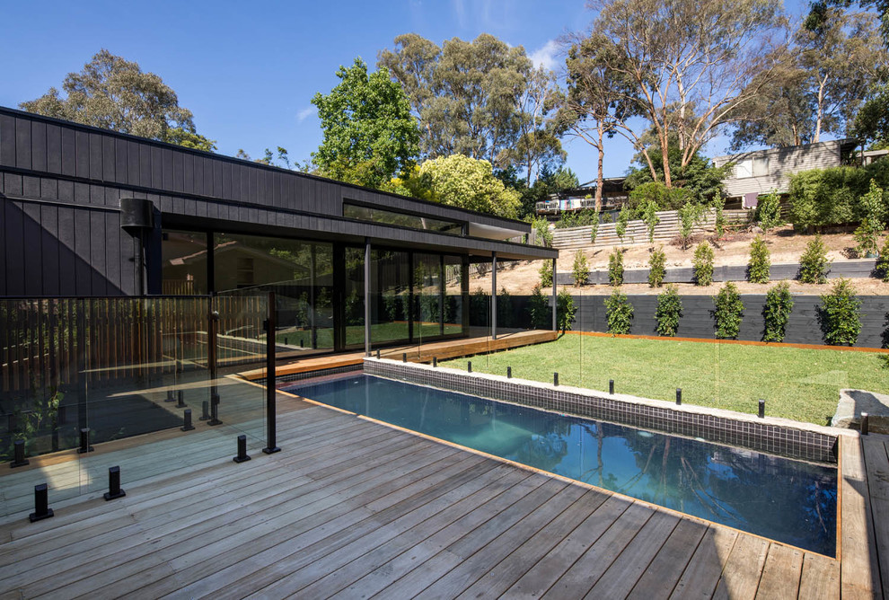 This is an example of a contemporary one-storey black house exterior in Melbourne with wood siding and a flat roof.
