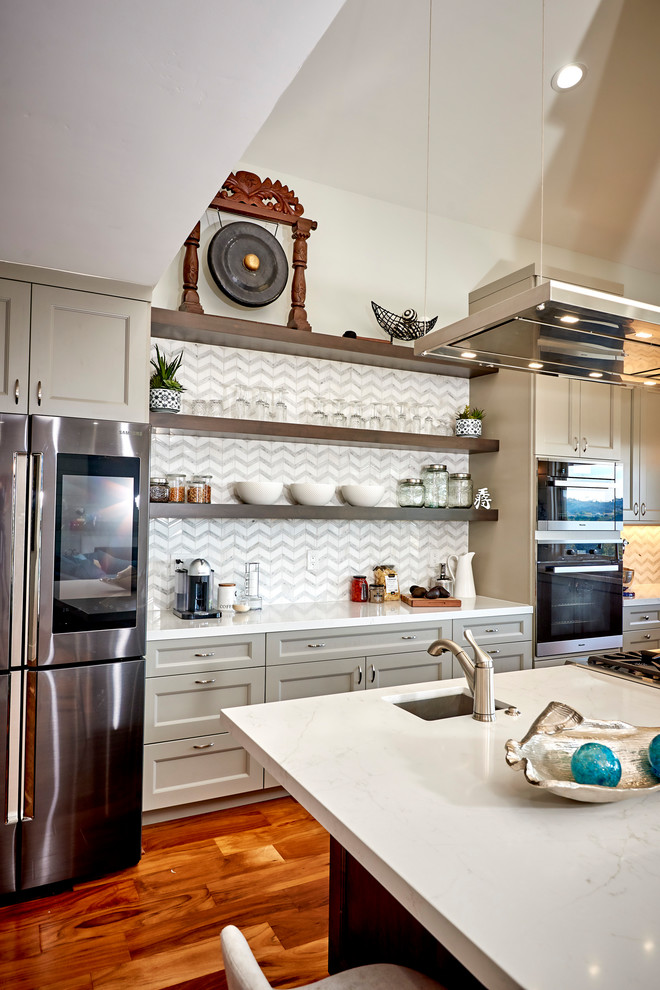 Open concept kitchen - large transitional l-shaped medium tone wood floor and brown floor open concept kitchen idea in Denver with an undermount sink, recessed-panel cabinets, gray cabinets, quartz countertops, white backsplash, marble backsplash, stainless steel appliances, an island and white countertops
