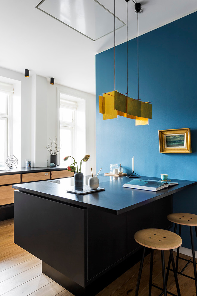 This is an example of a mid-sized scandinavian galley eat-in kitchen in Copenhagen with medium wood cabinets, medium hardwood floors, a peninsula, flat-panel cabinets and granite benchtops.