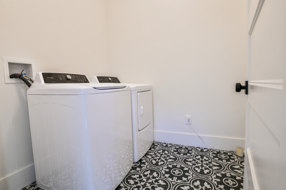 Imagen de cuarto de lavado lineal de estilo americano de tamaño medio con suelo laminado y lavadora y secadora juntas