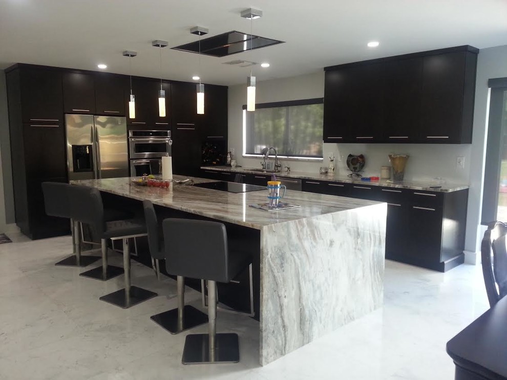 Photo of a mid-sized contemporary l-shaped eat-in kitchen in Miami with an undermount sink, flat-panel cabinets, black cabinets, granite benchtops, stainless steel appliances, ceramic floors, with island and grey floor.