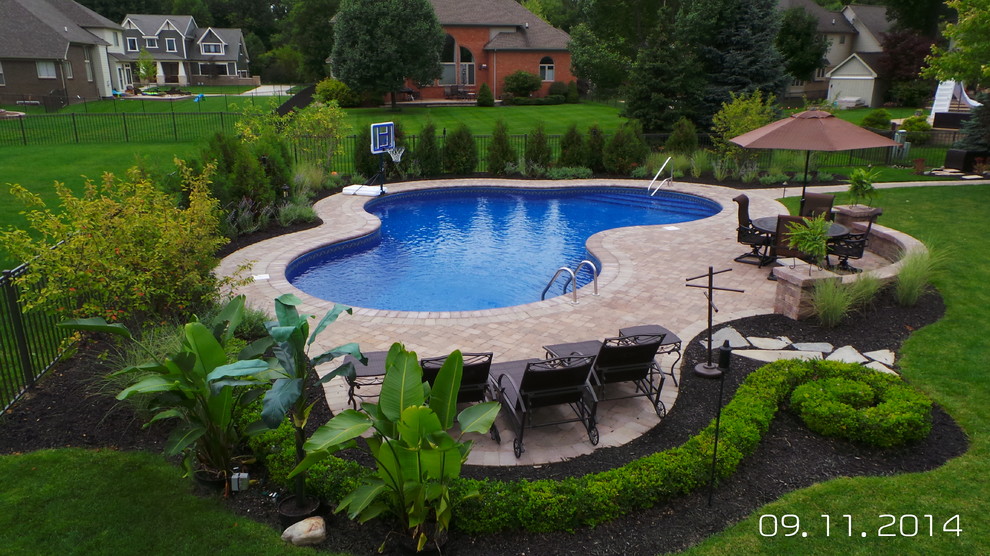 Inspiration for a mid-sized modern backyard custom-shaped pool in Detroit with brick pavers.