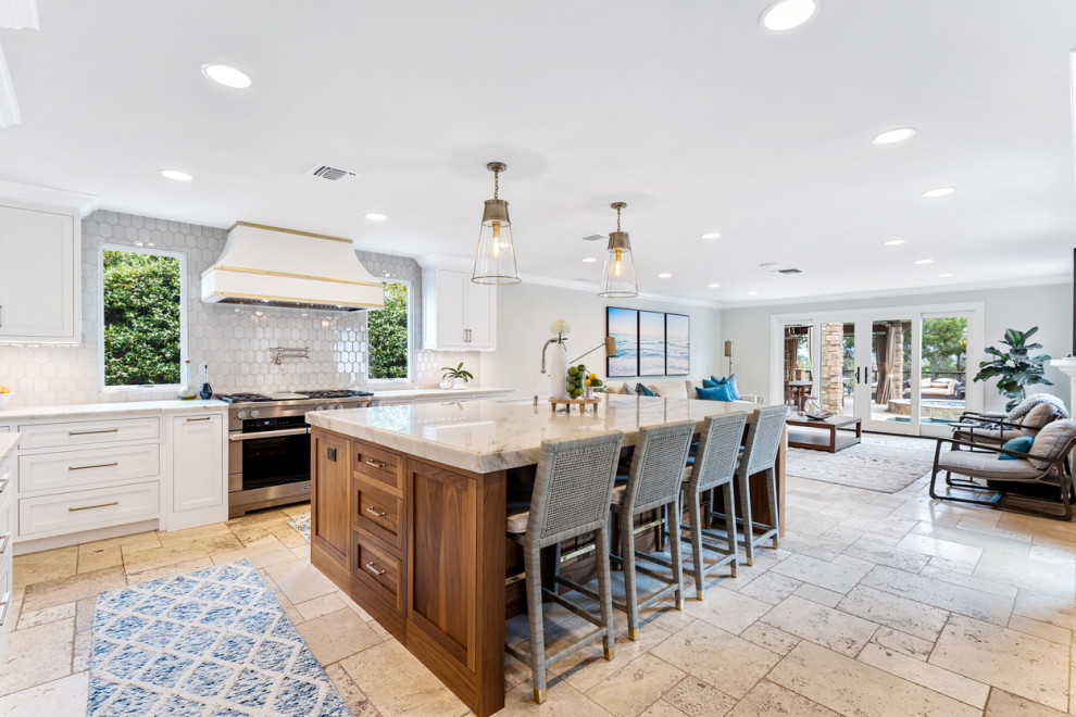 Photo of a large mediterranean u-shaped open plan kitchen in Los Angeles with a single-bowl sink, recessed-panel cabinets, white cabinets, quartzite benchtops, white splashback, stainless steel appliances, ceramic floors, with island, beige floor and multi-coloured benchtop.