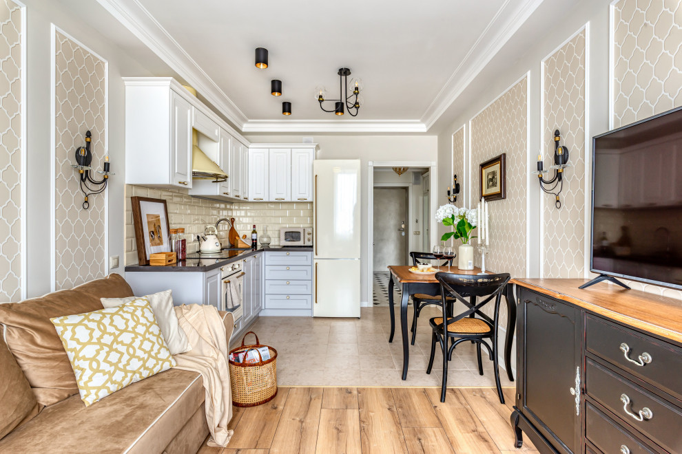 Mid-sized traditional l-shaped open plan kitchen in Moscow with raised-panel cabinets, white cabinets, beige splashback, subway tile splashback, beige floor and black benchtop.