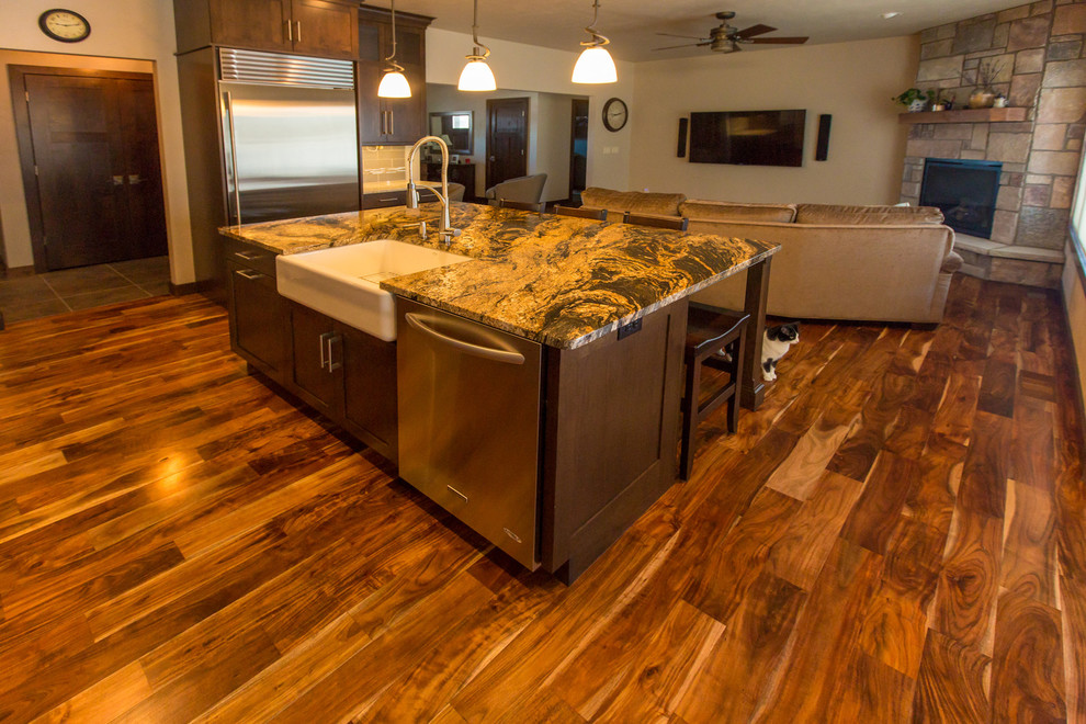 Open concept kitchen - large transitional l-shaped dark wood floor and brown floor open concept kitchen idea with a farmhouse sink, shaker cabinets, dark wood cabinets, granite countertops, beige backsplash, subway tile backsplash, stainless steel appliances and an island
