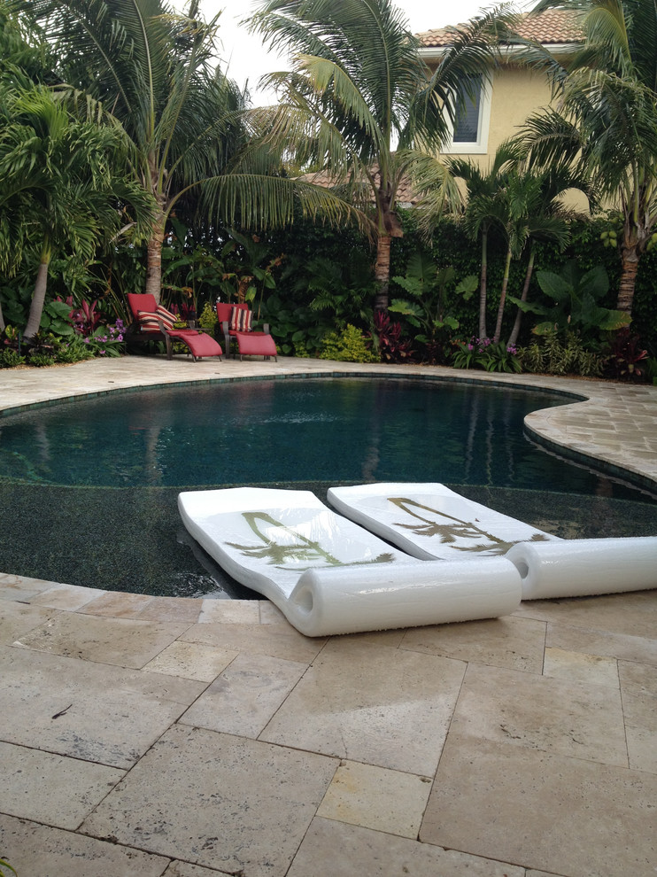 Inspiration for a mid-sized beach style backyard kidney-shaped natural pool in Miami with a hot tub and natural stone pavers.