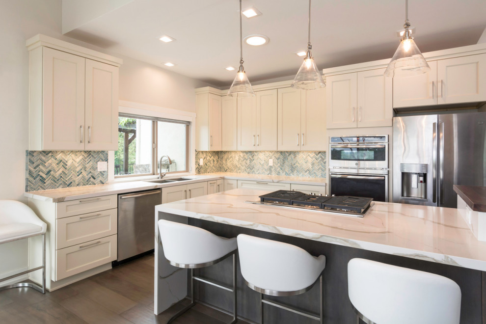 Example of a large transitional l-shaped dark wood floor eat-in kitchen design with an undermount sink, shaker cabinets, white cabinets, quartz countertops, blue backsplash, glass tile backsplash, stainless steel appliances, an island and white countertops