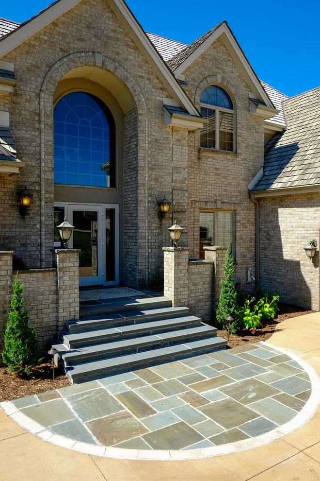 This is an example of a large traditional front door in Milwaukee with beige walls, slate floors, a single front door, a glass front door and blue floor.