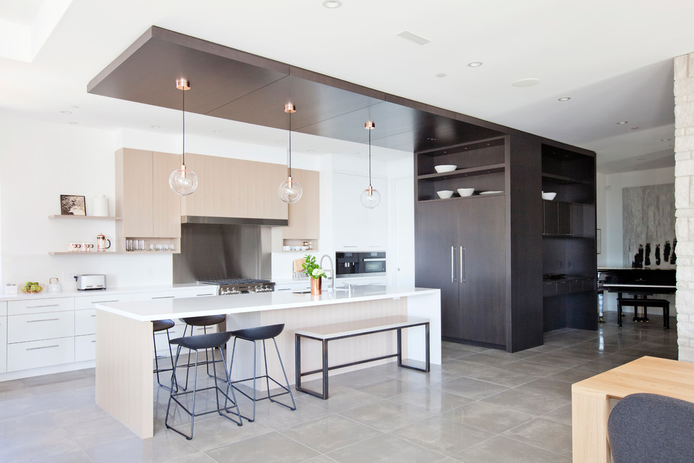 Photo of a large contemporary galley open plan kitchen in Vancouver with an undermount sink, flat-panel cabinets, light wood cabinets, quartz benchtops, white splashback, stone slab splashback, panelled appliances, porcelain floors and with island.