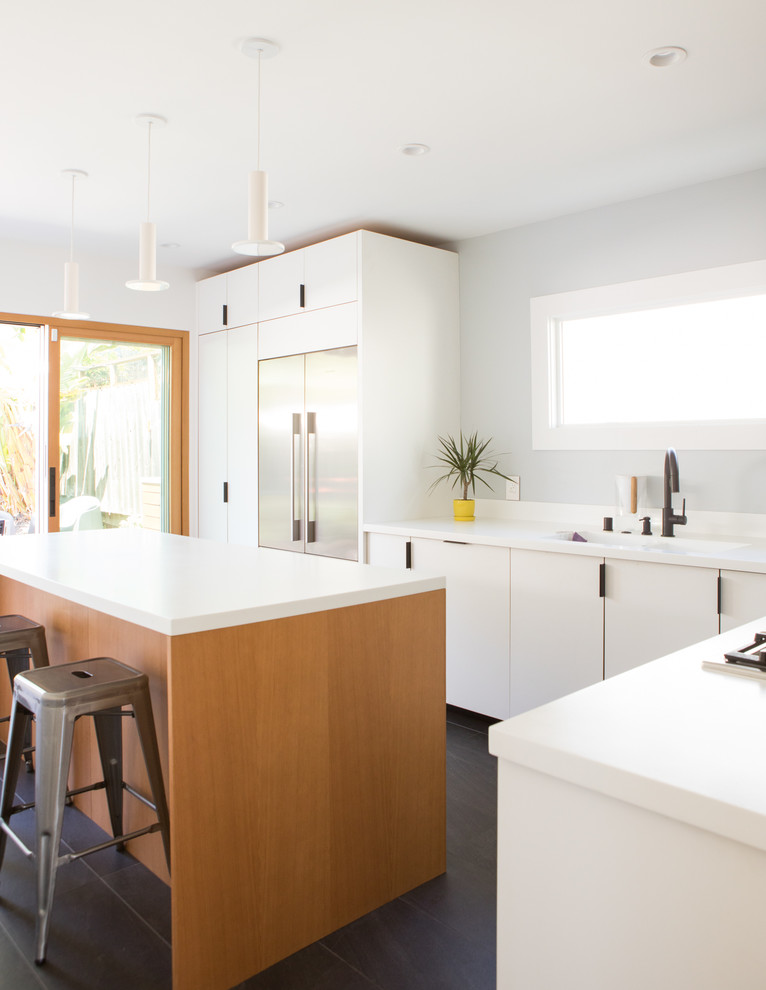 Photo of a mid-sized modern l-shaped separate kitchen in San Francisco with an integrated sink, flat-panel cabinets, white cabinets, solid surface benchtops, white splashback, stainless steel appliances, porcelain floors, with island, black floor and white benchtop.