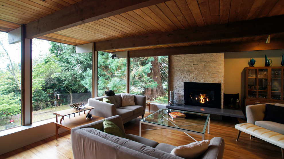 Mid-sized midcentury formal open concept living room in Seattle with beige walls, light hardwood floors, a standard fireplace, a freestanding tv and a stone fireplace surround.