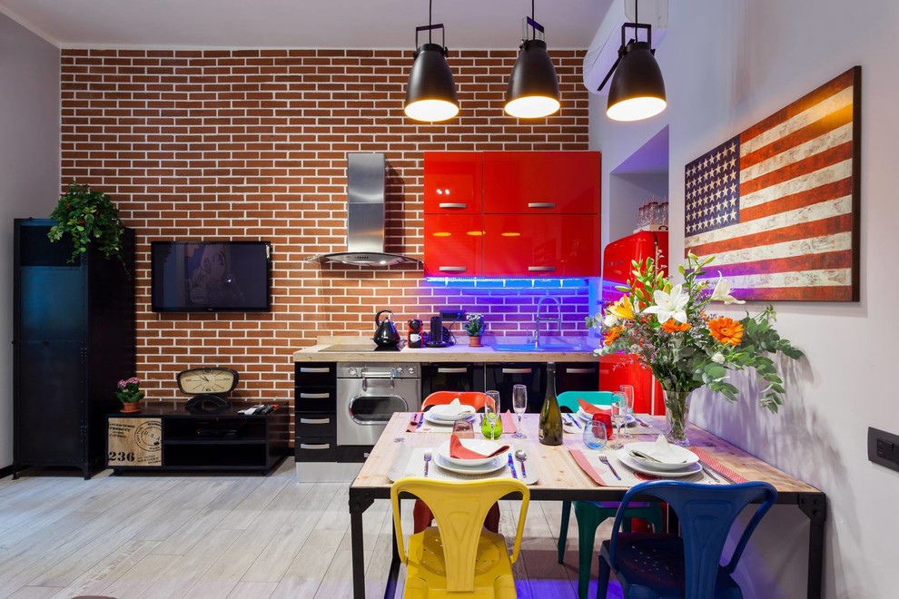 Inspiration for a small industrial open plan kitchen in Rome with a single-bowl sink, flat-panel cabinets, red cabinets, wood benchtops, red splashback, porcelain splashback, stainless steel appliances and porcelain floors.